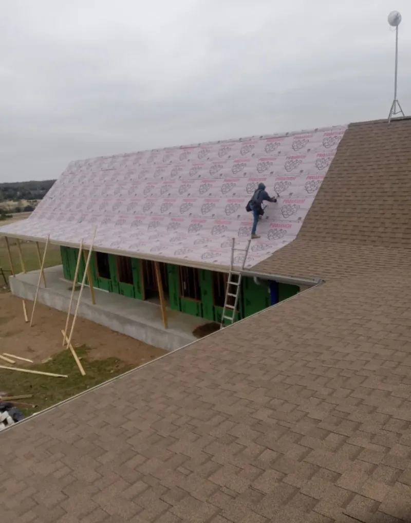 Worker preparing underlayment for a metal roof installation in Aiken
